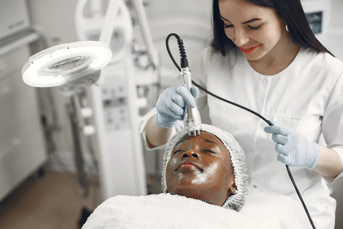 Esthetic technician performs radio frequency skin tightening service on relaxed client.