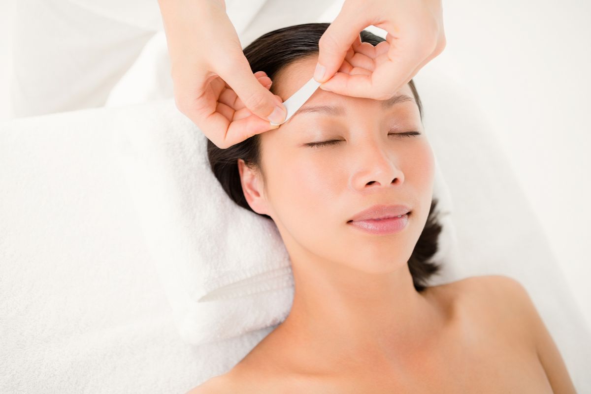 A client receives a professional eyebrow waxing treatment while lying comfortably at Namaste Skincare & Wellness in Henderson. This spa service add-on ensures smooth, clean results in a relaxing environment.
